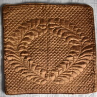 bronze coloured cushion cover with feather wreath quilted design