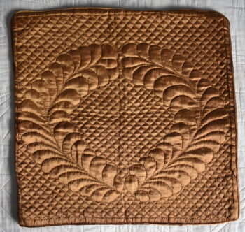 bronze coloured cushion cover with feather wreath quilted design